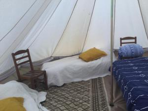 MellionnecEcoCamping d Hacadour的帐篷内的房间,配有两张床和两把椅子