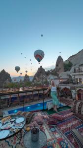 格雷梅本地岩洞酒店的站在带热气球的阳台上的女人