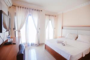 Oesapa-besarCHRYSANT HOTEL & RESORT的一间卧室设有一张床、一台电视和两个窗户。