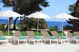 圣埃乌拉利亚Iberostar Selection Santa Eulalia Adults-Only Ibiza的一排躺椅和遮阳伞与海洋