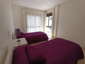阿尔加德萨Amplio apartamento en Portofino Alcaidesa的紫色床单的客房内的两张床