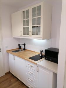希欧福克Kapitány apartman的厨房配有白色橱柜、水槽和微波炉