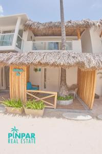 蓬塔卡纳Villa Blanca Beach Club的海滩上带稻草屋顶的房子