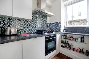 伦敦Bright and stylish apartment in trendy Islington by UnderTheDoormat的厨房配有白色橱柜和炉灶烤箱。