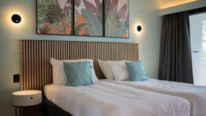 威廉斯塔德Blue Bay Lodges的一间卧室配有两张带白色床单和蓝色枕头的床。