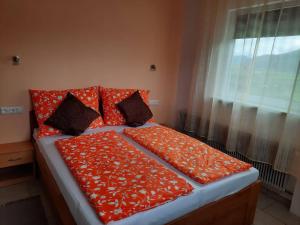 圣卡尼兹Pension Horvath的一张带橙色床单和枕头的床,配有窗户