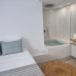 伊奥斯乔拉Drimoni Boutique的白色的浴室设有浴缸、床和地毯。