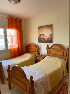 罗萨斯Apartamento tranquilo en Roses centro cerca de la playa Costa brava的卧室内的两张床,配有橙色窗帘