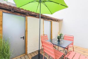兰斯Art Déco Champagne & Spa的庭院内一张桌子和椅子,上面有一把绿伞