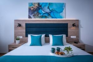赫索尼索斯福拉瑞酒店的一张带蓝色枕头的床和一盘食物