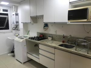 阿雷格里港Apartamento p/ 8 com garagem churasqueira e piscina的小厨房配有白色橱柜和水槽