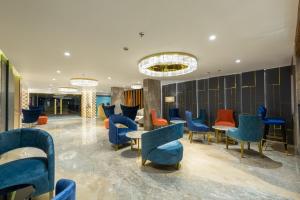 艾哈迈达巴德那兰陀酒店的大堂设有蓝色和橙色的椅子和桌子
