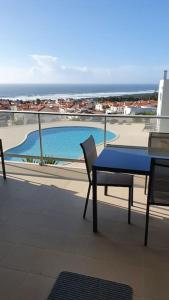 纳扎雷Brisa do Mar Ap.的阳台配有蓝色的桌椅,设有游泳池