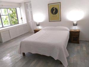 坎昆casa HIKURI的卧室配有白色的床和两盏灯。