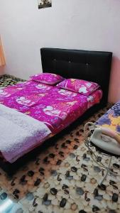 KodiangHOMESTAY UMI KODIANG的一张带紫色棉被和地板的床