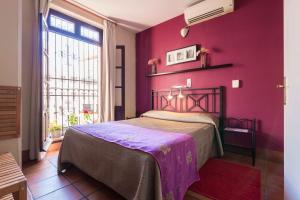 塞维利亚拉斯克鲁塞斯庭院酒店的卧室设有紫色墙壁、一张床和一个窗户