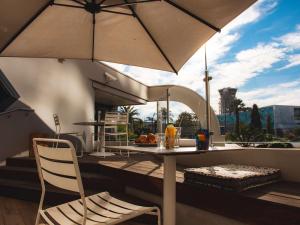 尼斯钟楼尼斯机场酒店的阳台配有桌椅和遮阳伞