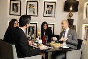 贝鲁特阿什拉菲耶皇家郁金香酒店的一群人坐在餐馆的桌子旁