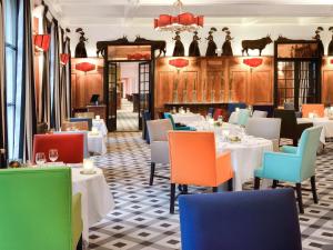 阿尔勒Hôtel & Spa Jules César Arles - MGallery Hotel Collection的餐厅设有白色的桌子和五颜六色的椅子