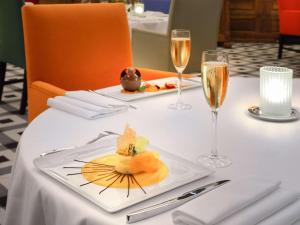 阿尔勒Hôtel & Spa Jules César Arles - MGallery Hotel Collection的一张桌子,上面放着一盘食物和一杯香槟