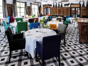 阿尔勒Hôtel & Spa Jules César Arles - MGallery Hotel Collection的一间设有白色桌子和五颜六色椅子的用餐室