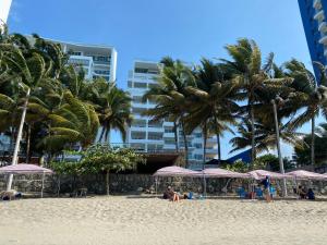 通苏帕Suites de Lujo Playa Azul的海滩上种有棕榈树和遮阳伞