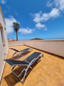 巴尔韦尔德Apartamento La Villa的棕榈树阳台的一对椅子