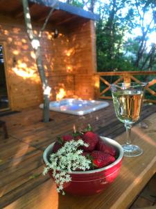 ZalaújlakŐzlak Lombház的木桌旁放着一碗草莓和一杯葡萄酒