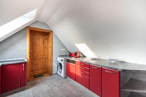 凯斯特海伊Buzavirág Apartman的阁楼厨房配有红色橱柜和洗衣机。