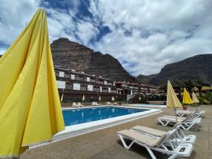 巴耶格兰雷伊Apartamentos Los Tarajales的一个带游泳池和椅子的度假村和一座山
