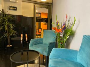 拉巴特RENT-INN Suites Hotel的大堂设有蓝色的椅子、桌子和鲜花