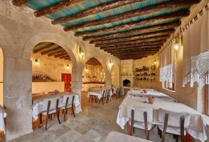 内夫谢希尔Charm Of Cappadocia Cave Suites的大楼内一家带白色桌椅的餐厅