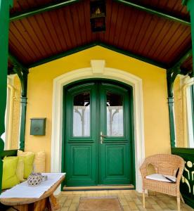 阿特湖畔努斯多夫Cottage am Attersee的黄色房子的绿色门,带桌子