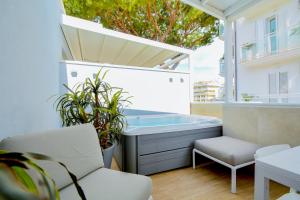 里乔内Prime Blue Suite - Appartamenti con jacuzzi privata的阳台设有浴缸、椅子和植物