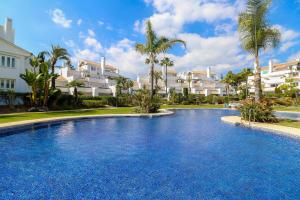 马贝拉Family apartment with garden- Los Monteros Palm Beach的一座大型游泳池,位于部分建筑前