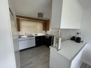 新罗姆尼Romney Sands Holiday Apartment的厨房配有白色冰箱和水槽