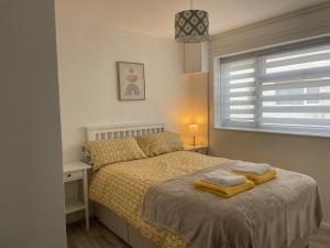 新罗姆尼Romney Sands Holiday Apartment的一间卧室配有一张床,上面有两条毛巾