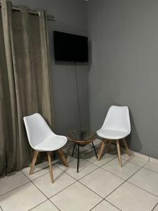 索韦托Tshukudu Guesthouse的客房内的2把白色椅子和1张桌子