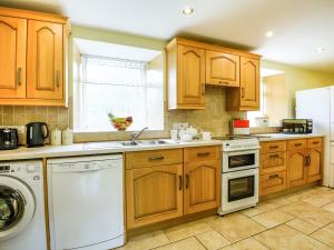 LlanegrynY Bwthyn的厨房配有木制橱柜和白色洗碗机。