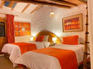 库斯科大地之母旅馆的一间卧室配有两张带橙色和白色床单的床