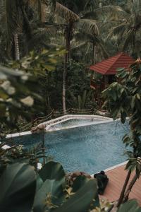 塞莱马德加Kusfarm Bali的一个带凉亭和树木的游泳池