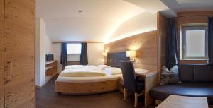 奥蒂塞伊Hotel Garni Vanadis的一间卧室配有一张床、一张桌子和一把椅子