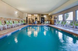 堪萨斯城近欢闹世界康福特茵套房酒店的一座带椅子和蓝色水的游泳池