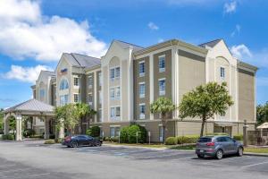 默特尔比奇Comfort Suites Myrtle Beach Central的停车场内停放汽车的大型建筑