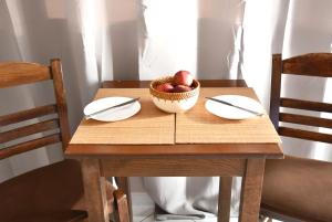 里科索翁Anemomylos Apartments的一张桌子,上面放两个盘子和一碗苹果