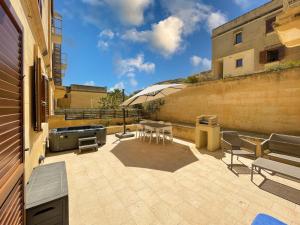 MġarrGee9Teen at Fort Chambray的一个带桌椅和烧烤设施的庭院