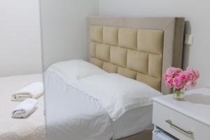 萨兰达Saranda Landscape的白色卧室,配有床和镜子内的鲜花