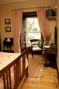韦克斯福德Glendine Country House Wexford的一间卧室配有一张床、一个窗口和一张书桌