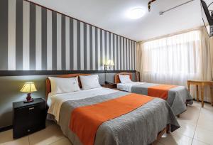 特鲁希略Recreo Hotel的配有条纹墙壁的酒店客房内的两张床