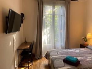 巴塞罗那Rooms Aribau的一间卧室配有一张床、一台电视和一个窗口
